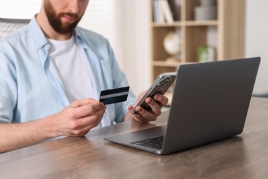 Photo of Online banking. Man with credit card and laptop paying purchase at table, closeup