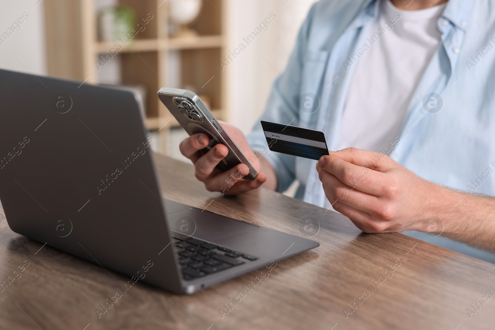 Photo of Online banking. Man with credit card and laptop paying purchase at table, closeup