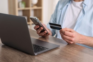 Online banking. Man with credit card and laptop paying purchase at table, closeup