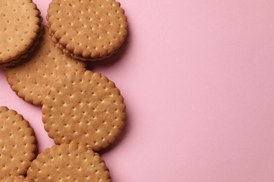 Tasty sandwich cookies on pink background, top view. Space for text