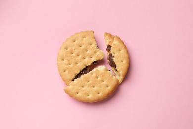 Piece of tasty sandwich cookie on pink background, top view