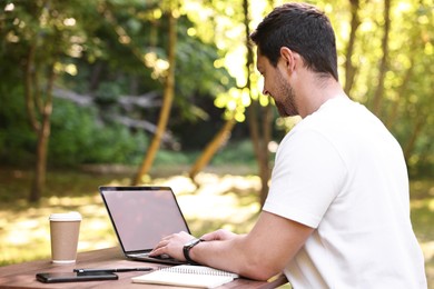Photo of Freelancer working with laptop at table outdoors on sunny day. Remote job