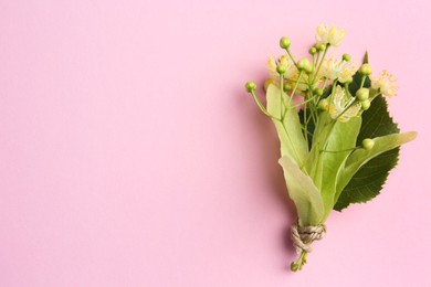 Beautiful linden blossoms and green leaves on pink background, top view. Space for text