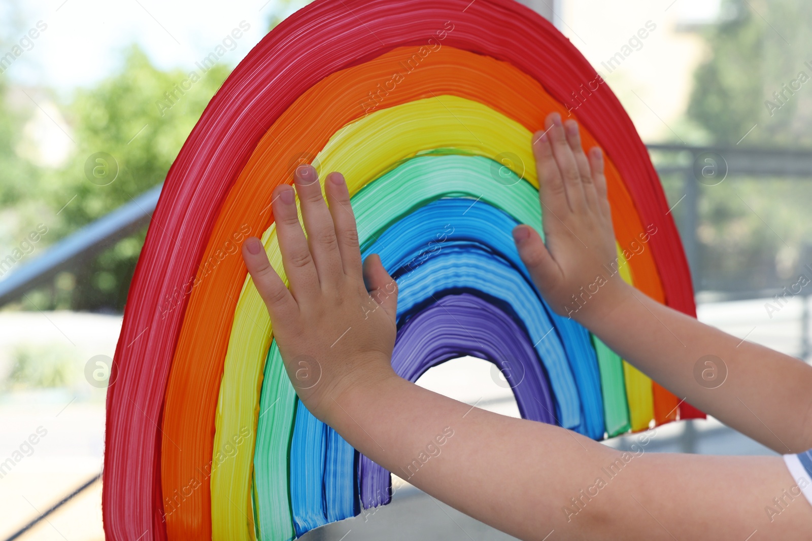 Photo of Little boy touching picture of rainbow on window, closeup