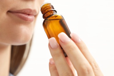 Aromatherapy. Woman with bottle of essential oil on light background, closeup