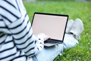 Photo of Freelancer working with laptop on green grass outdoors, closeup. Remote job