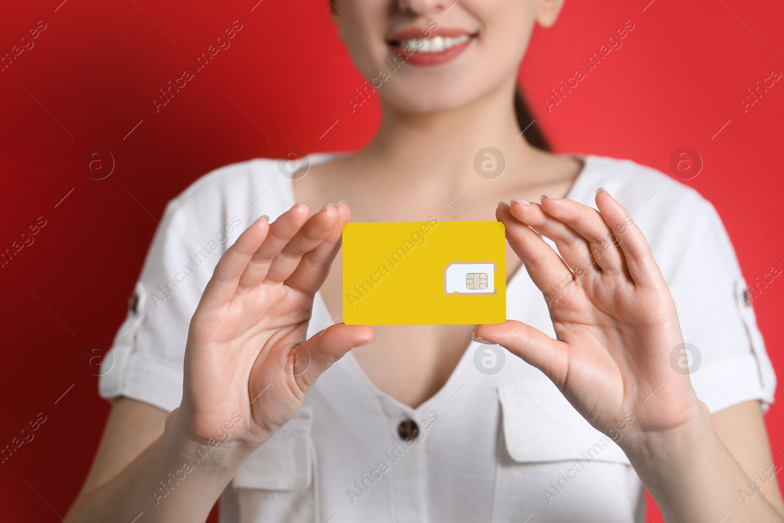 Photo of Woman holding SIM card on red background, closeup