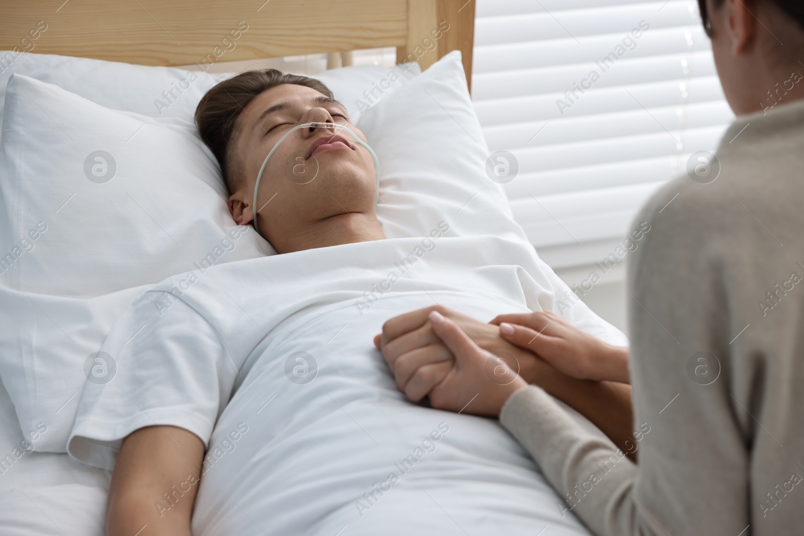 Photo of Coma patient. Sad young woman near her husband in hospital