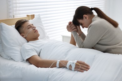 Coma patient. Sad young woman near her husband in hospital