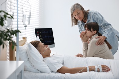 Photo of Coma patient. Sad women near unconscious young man in hospital