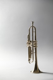 Photo of Shiny trumpet on light grey background. Wind musical instrument