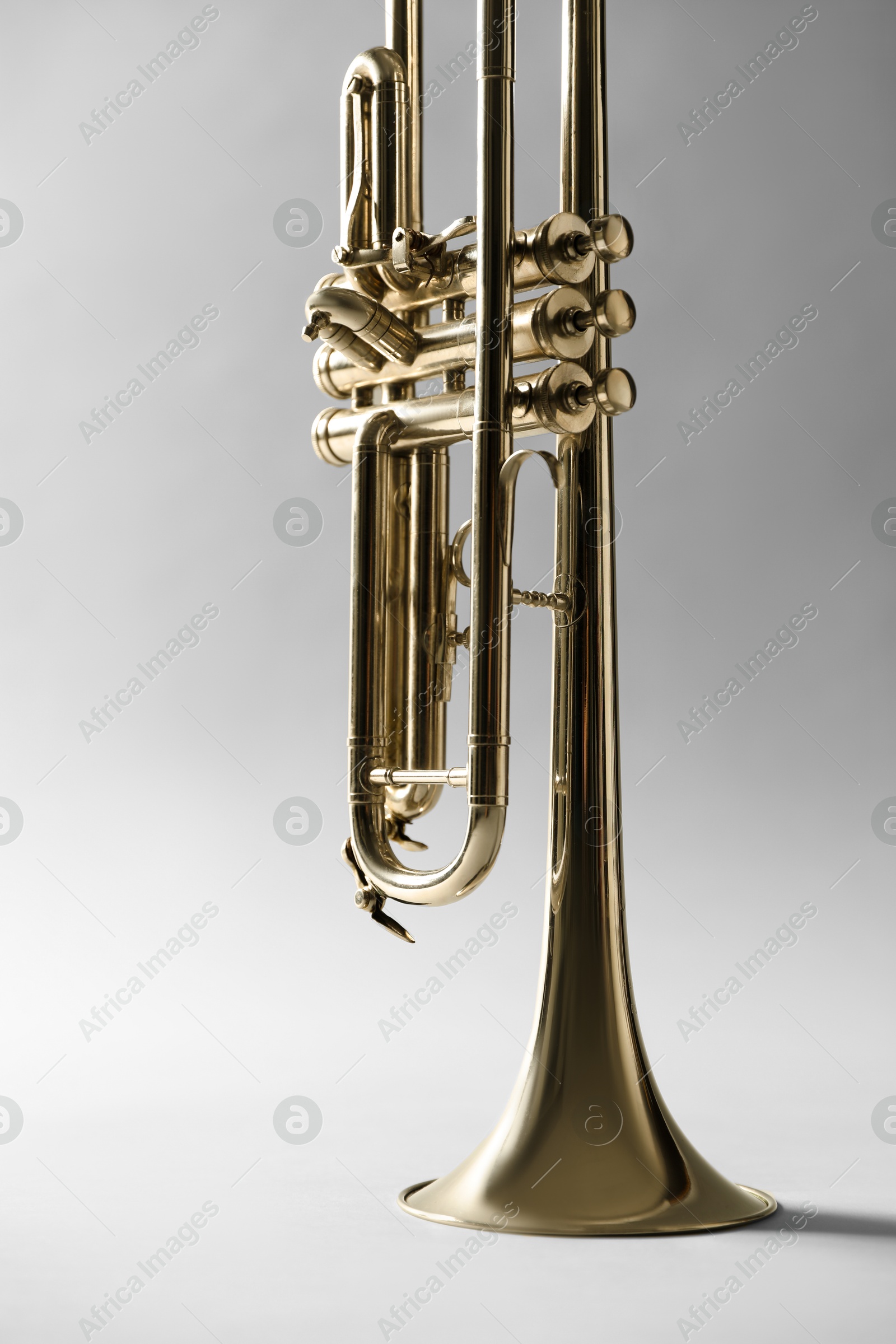 Photo of Shiny trumpet on light grey background. Wind musical instrument