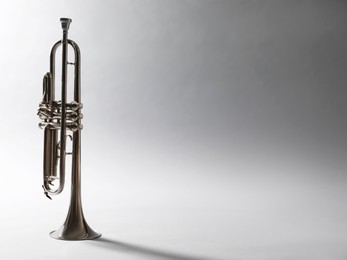 Shiny trumpet on light grey background, space for text. Wind musical instrument