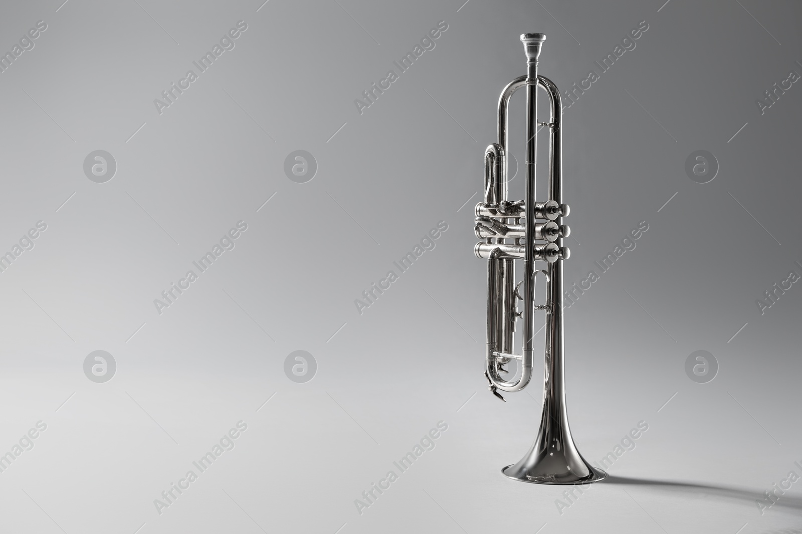 Photo of Shiny trumpet on light grey background, space for text. Wind musical instrument