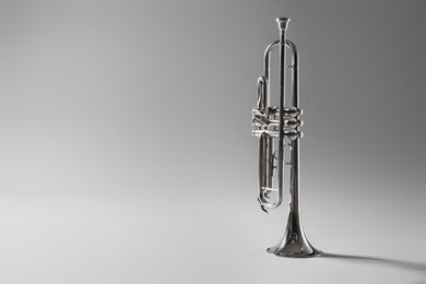 Shiny trumpet on light grey background, space for text. Wind musical instrument