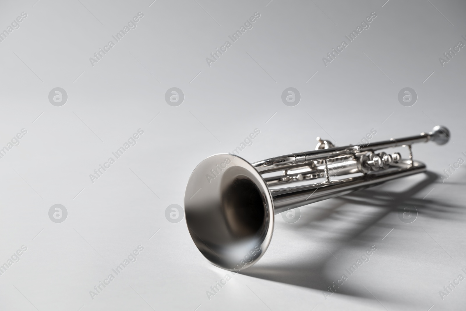 Photo of Shiny trumpet on light grey background, space for text. Wind musical instrument