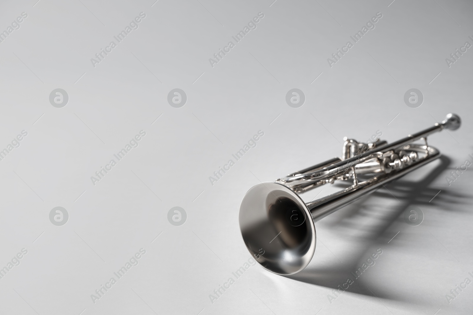 Photo of Shiny trumpet on light grey background, space for text. Wind musical instrument