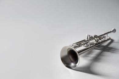 Shiny trumpet on light grey background, space for text. Wind musical instrument