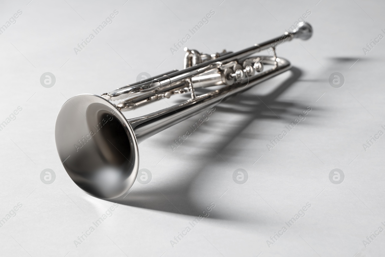 Photo of Shiny trumpet on light grey background, space for text. Wind musical instrument