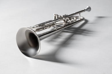 Shiny trumpet on light grey background, space for text. Wind musical instrument