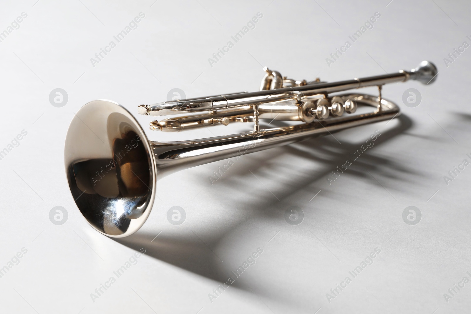 Photo of Shiny trumpet on light grey background, space for text. Wind musical instrument