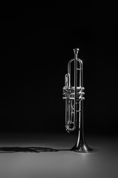 Photo of Shiny trumpet on dark background. Wind musical instrument