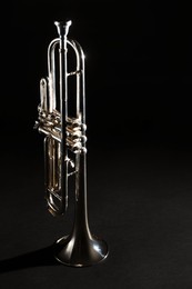 Photo of Shiny trumpet on dark background. Wind musical instrument