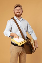 Photo of Happy young postman with leather bag delivering letters on brown background