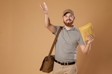 Photo of Happy young postman with leather bag delivering letters on brown background