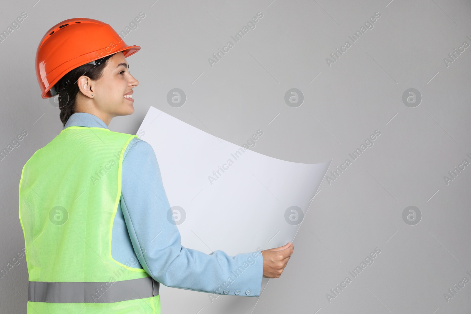 Photo of Engineer in hard hat with draft on grey background, space for text