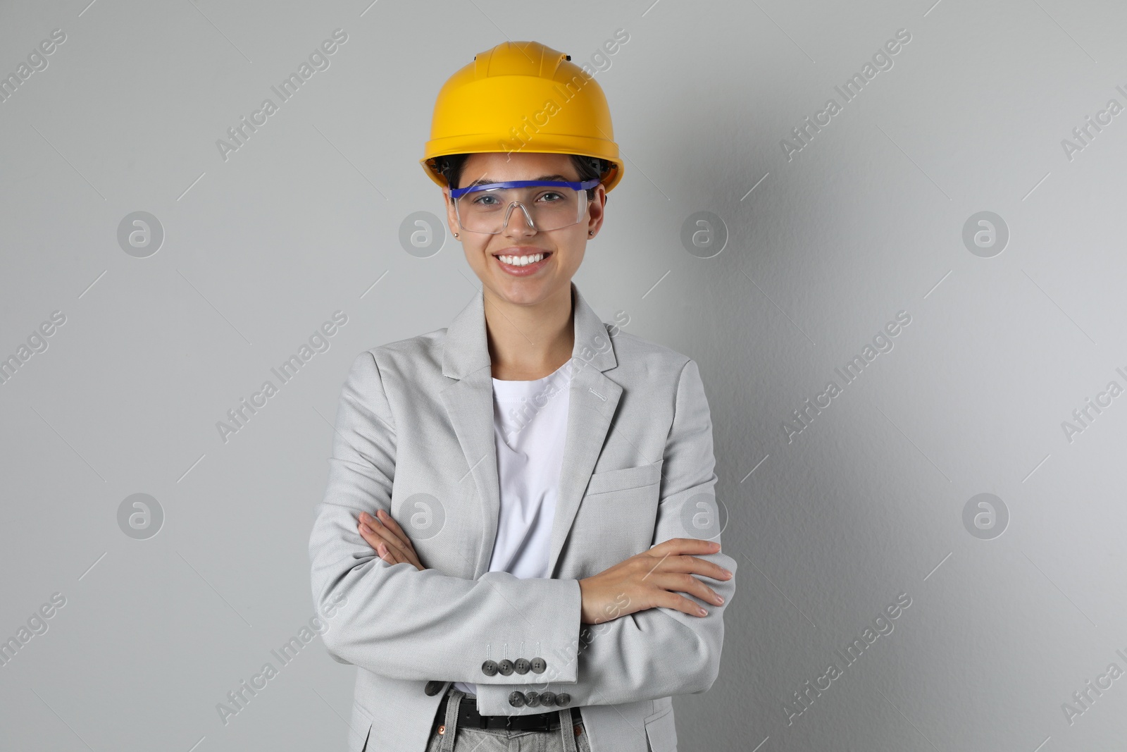 Photo of Engineer in hard hat and goggles on grey background