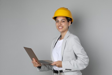 Photo of Engineer in hard hat with laptop on grey background