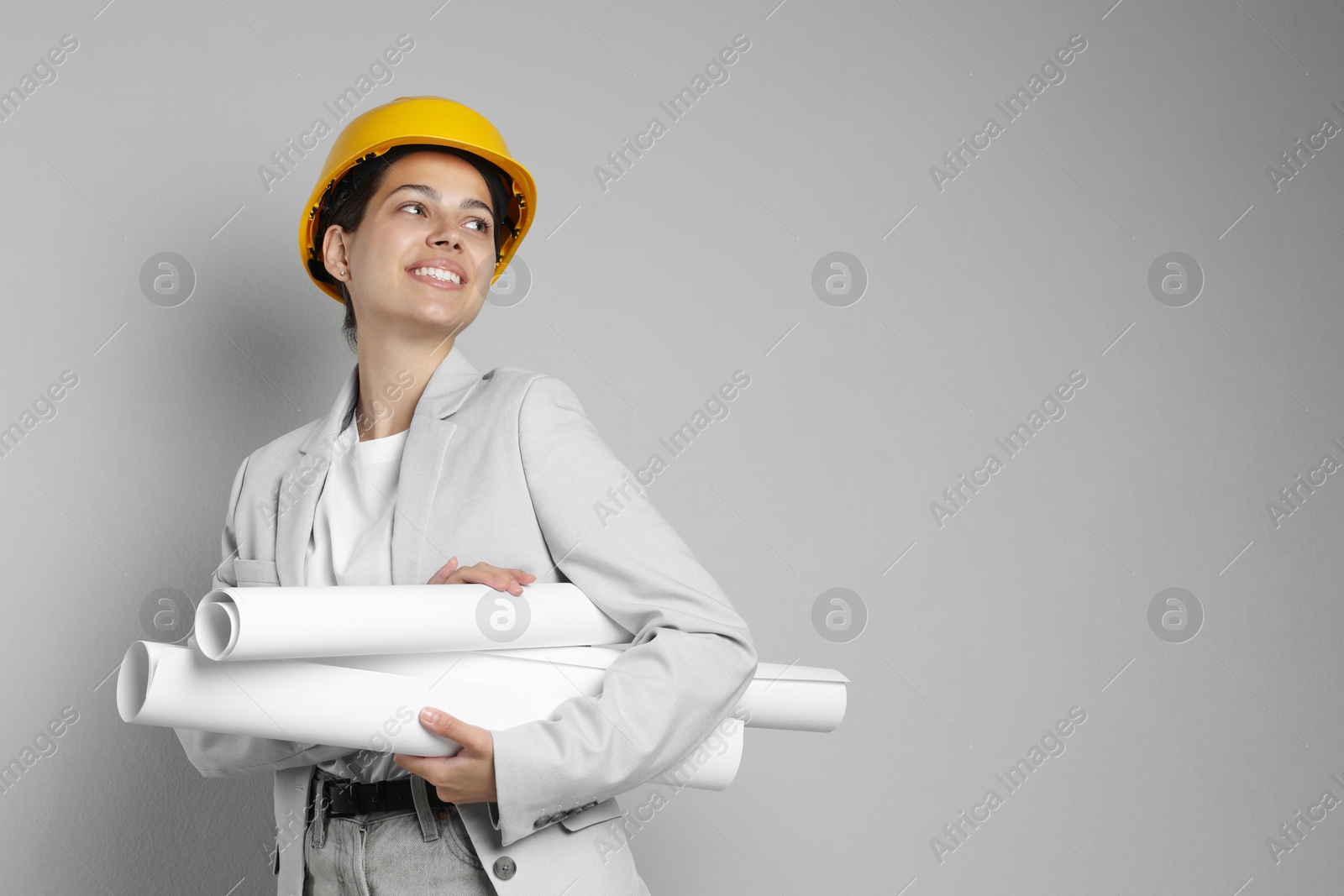 Photo of Engineer in hard hat with drafts on grey background, space for text