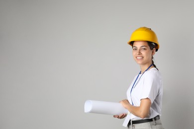 Photo of Engineer in hard hat with draft on grey background, space for text