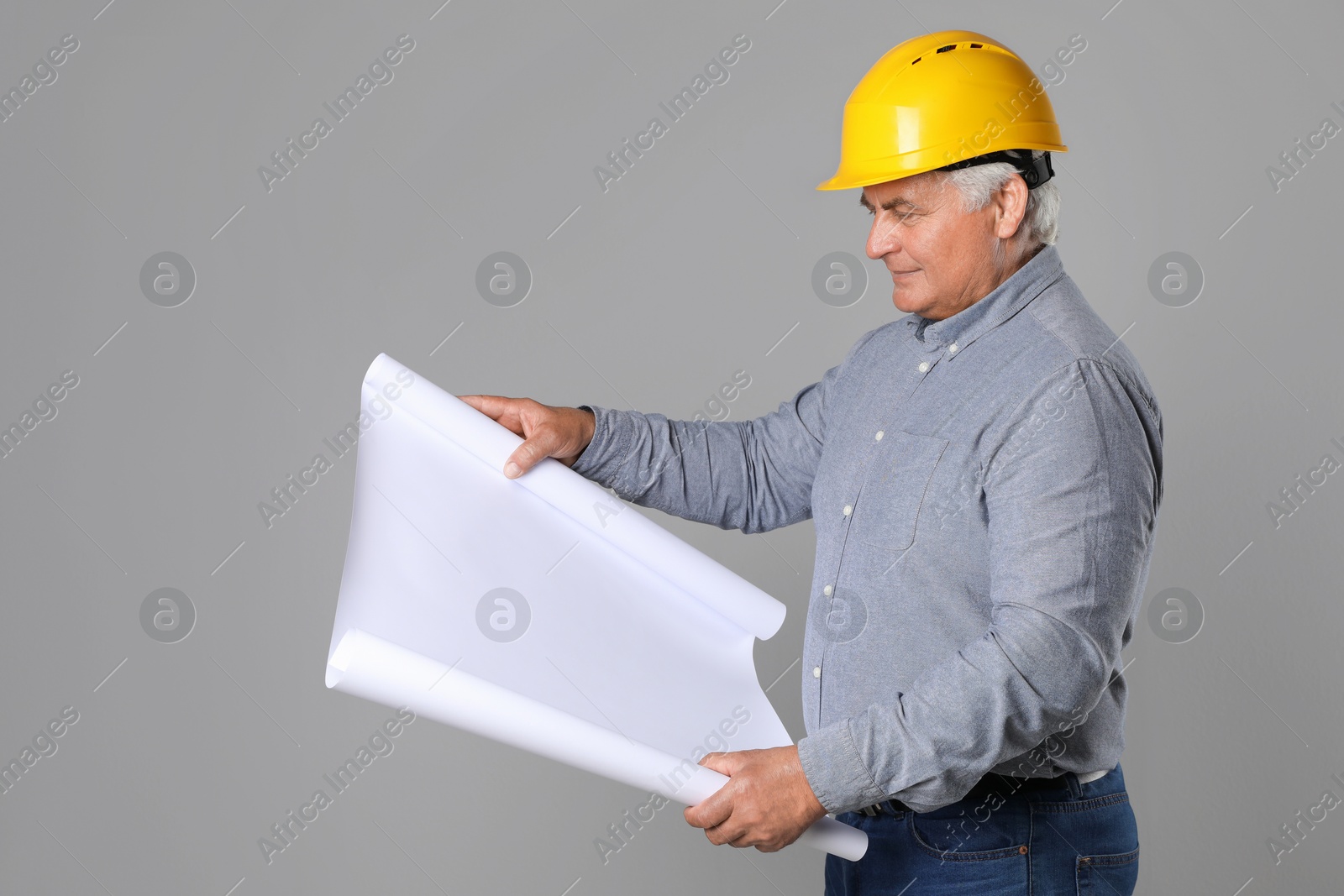 Photo of Engineer in hard hat with draft on grey background