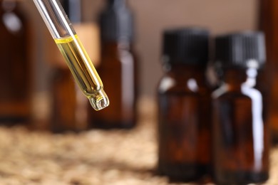 Photo of Essential oil dripping from pipette against blurred background, closeup. Space for text