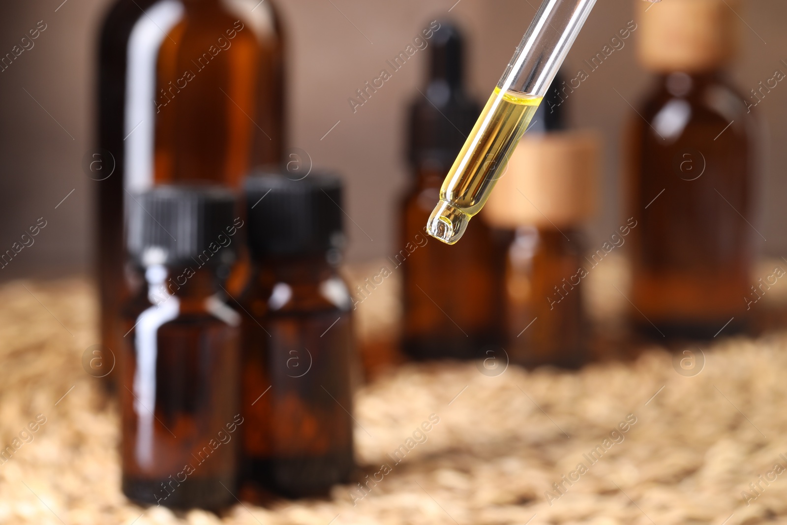 Photo of Essential oil dripping from pipette against blurred background, closeup. Space for text