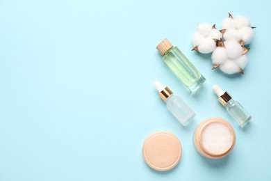 Photo of Different cosmetic products and cotton flowers on light blue background, flat lay. Space for text