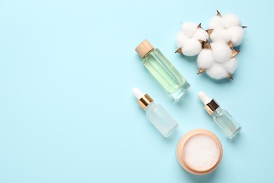 Photo of Different cosmetic products and cotton flowers on light blue background, flat lay. Space for text