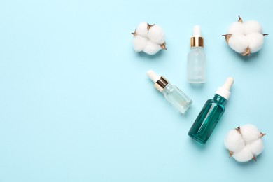 Photo of Different cosmetic products and cotton flowers on light blue background, flat lay. Space for text