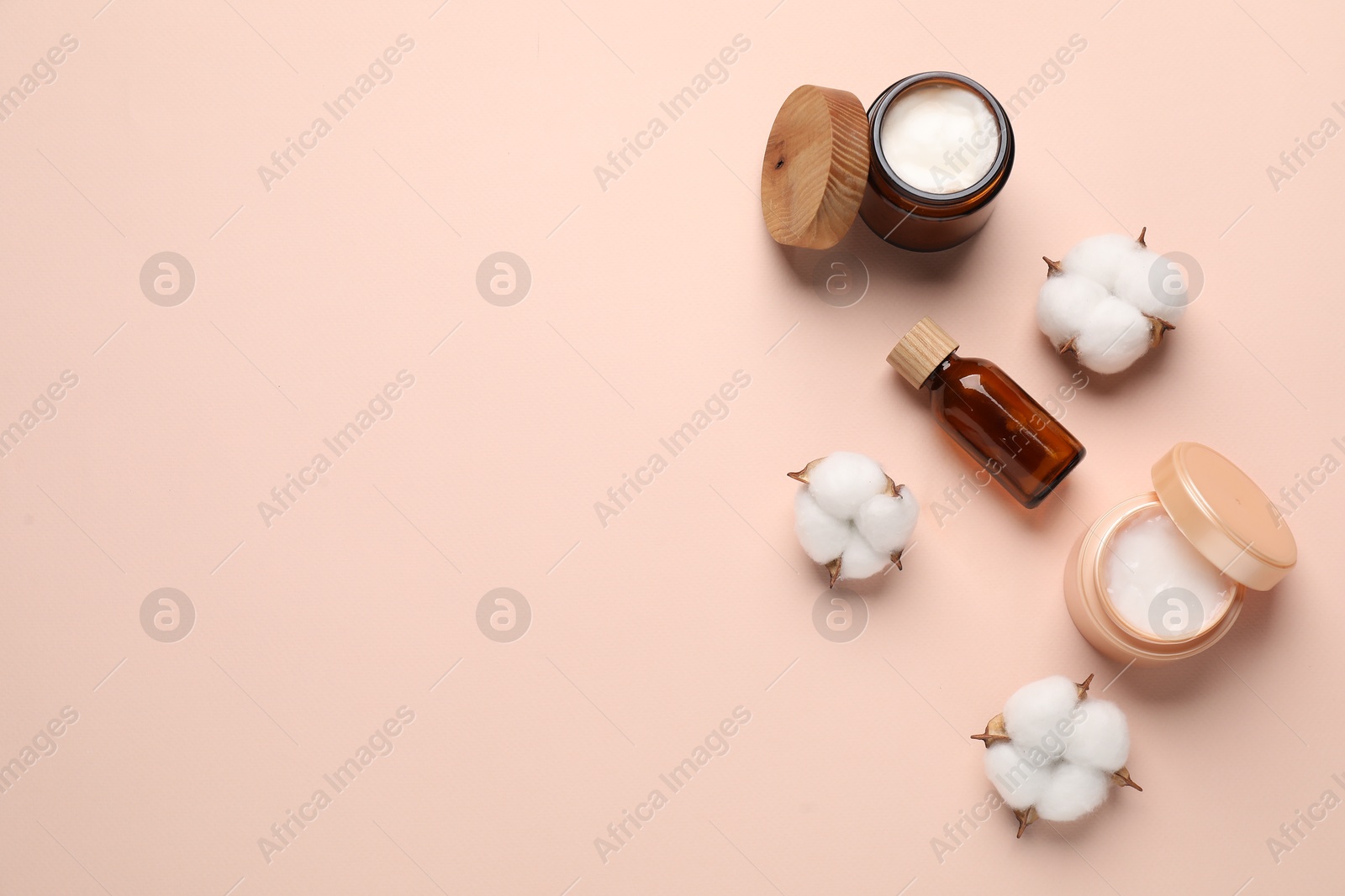 Photo of Different cosmetic products and cotton flowers on beige background, flat lay. Space for text