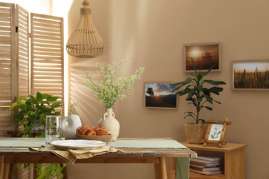 Photo of Clean tableware, flowers and fresh pastries on table in stylish dining room