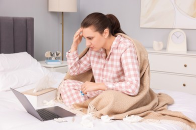 Photo of Sick woman with pills having online consultation with doctor via laptop at home
