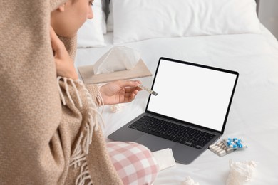 Photo of Sick woman with thermometer having online consultation with doctor via laptop at home