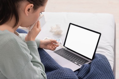 Sick woman with thermometer having online consultation with doctor via laptop at home