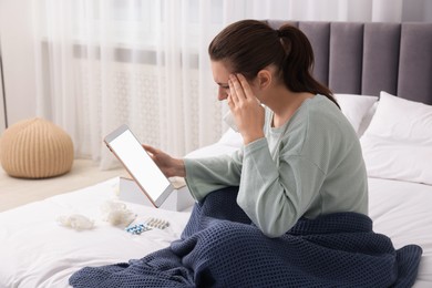 Sick woman having online consultation with doctor via tablet at home