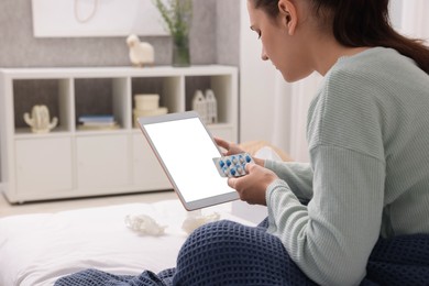 Sick woman with pills having online consultation with doctor via tablet at home