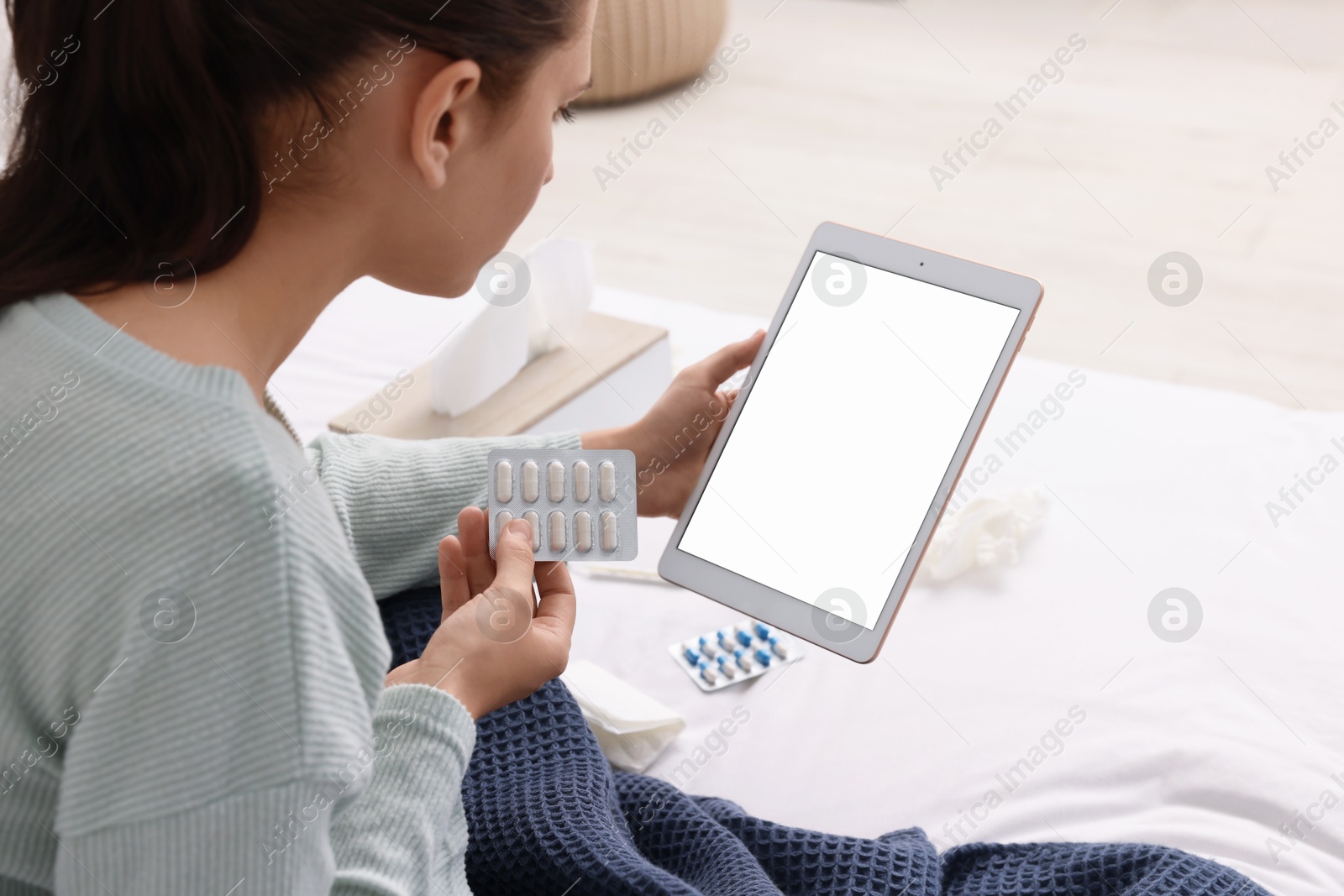 Photo of Sick woman with pills having online consultation with doctor via tablet at home