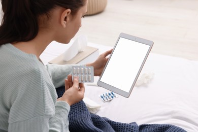 Sick woman with pills having online consultation with doctor via tablet at home