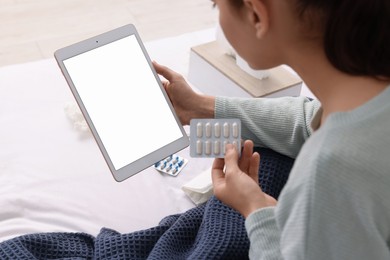 Photo of Sick woman with pills having online consultation with doctor via tablet at home